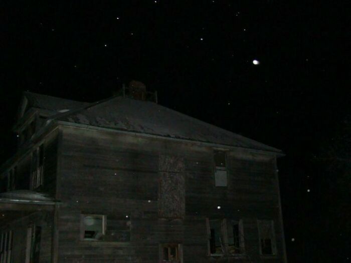 Dark, abandoned house at night with broken windows and eerie atmosphere fitting terrifying photos and stories.