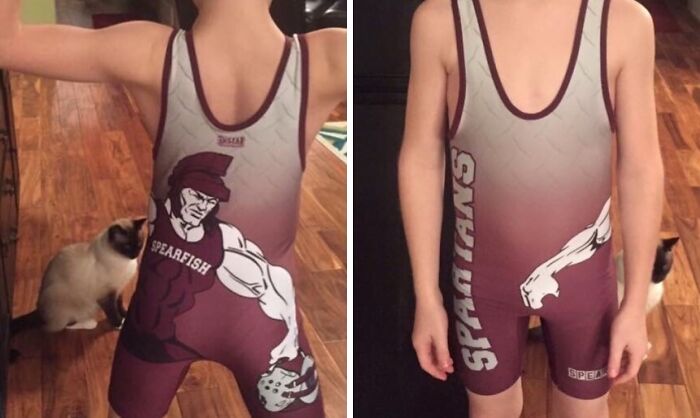 Child wearing a maroon Spartans uniform with a muscle design alongside a cat on a wooden floor, showing funny uniform wear.