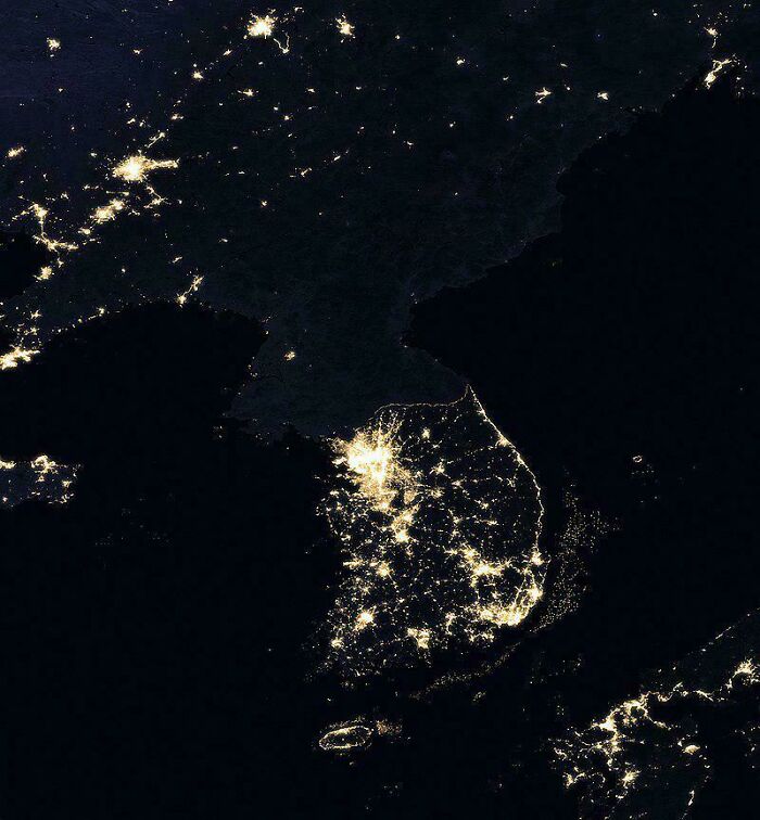 Night satellite image showing urban hell lit areas and population centers across a peninsula and nearby regions.