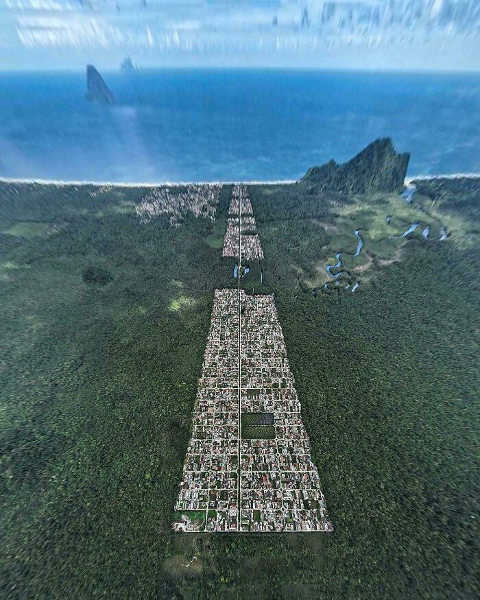 Aerial view of a dense urban hell echo chamber area surrounded by thick forest and coastline in the distance.