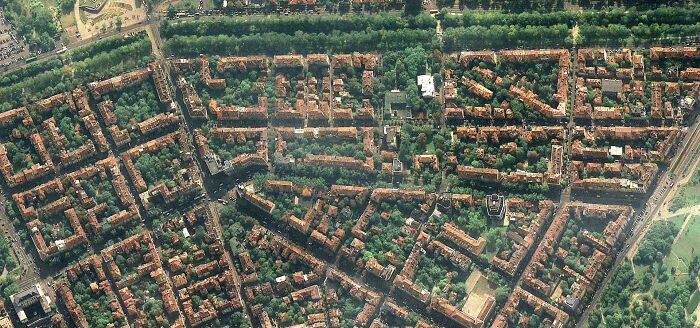 Aerial view of dense urban neighborhood with tightly packed buildings and green spaces illustrating urban hell concept.