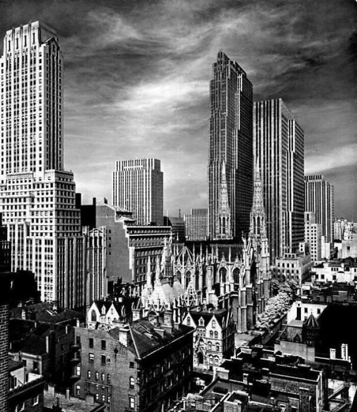 Black and white cityscape showing urban hell with towering buildings and dense urban architecture under a cloudy sky