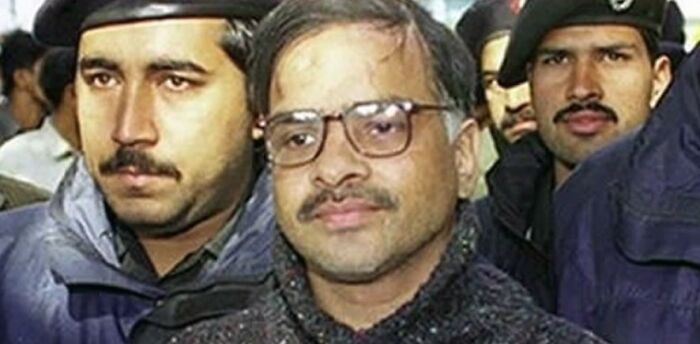 Man with glasses surrounded by serious police officers in a tense and terrifying photo scene.