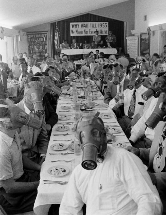 Men wearing gas masks at a formal gathering, highlighting terrifying photos and stories from the past.