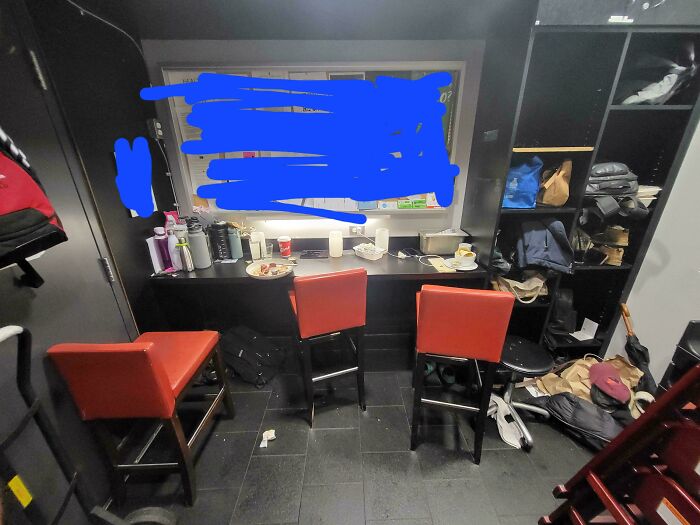 Prison-like break room with cluttered shelves, worn chairs, and limited space, showing one of the worst break rooms ever.