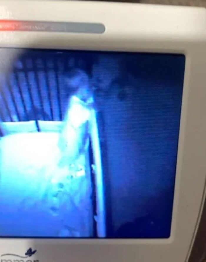 Baby captured in a night vision monitor with a ghostly figure nearby in a terrifying photo scene.