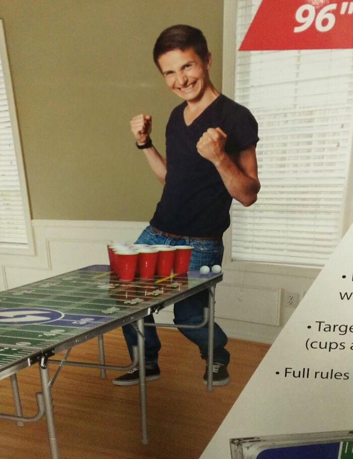 Teen celebrating with fists raised next to a beer pong table showing a clear Photoshop fail with floating legs.