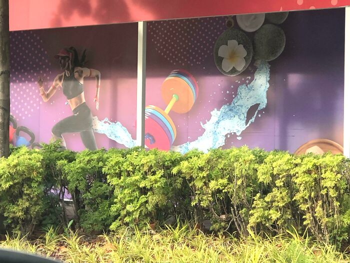 Image of a fitness mural showing a running woman with a poorly edited water splash and dumbbell Photoshop fail.
