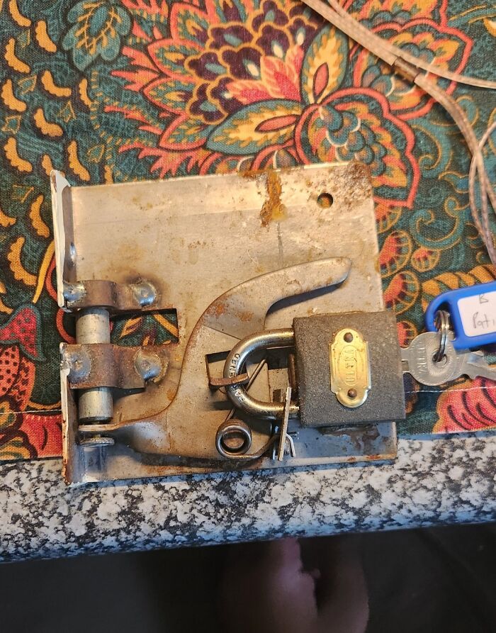 Rusty and broken lock mechanism with a padlock and keys, showcasing a landlord fail in rental property security.