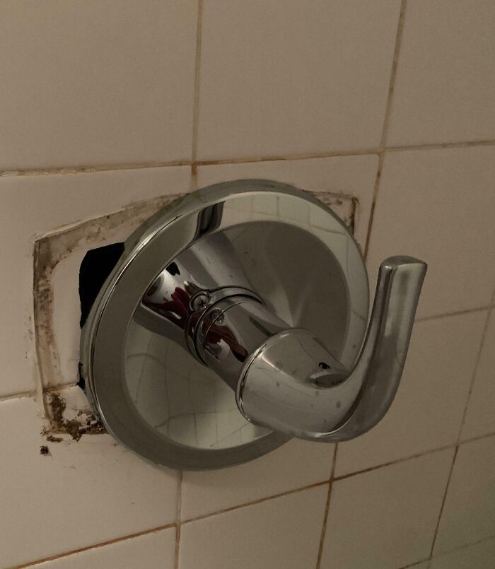 Broken shower handle with exposed wall and mold on tiles, showing poor maintenance by landlords in rental properties.