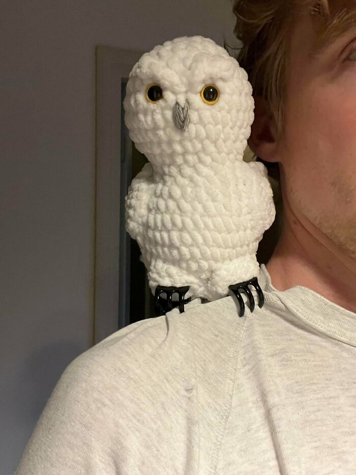 Crocheted white owl perched on a person's shoulder showcasing detailed texture in a handmade crocheting project.