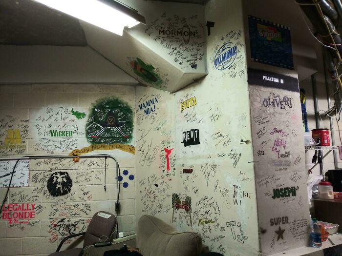 Break room walls covered with theater show signatures and posters, resembling one of the worst break rooms ever.