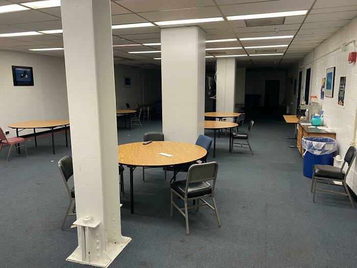 Sparse break room with plain tables and chairs, resembling a prison environment in one of the worst break rooms ever.