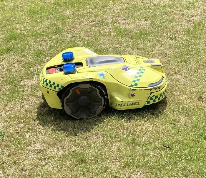 Small automated yellow ambulance robot moving on grass, showcasing innovative Danish technology and design.