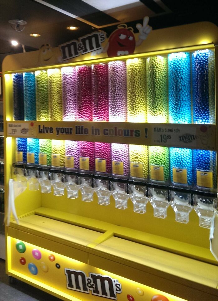 Colorful candy dispenser filled with M&M's, showcasing vibrant assortments in a bright, modern Danish setting.