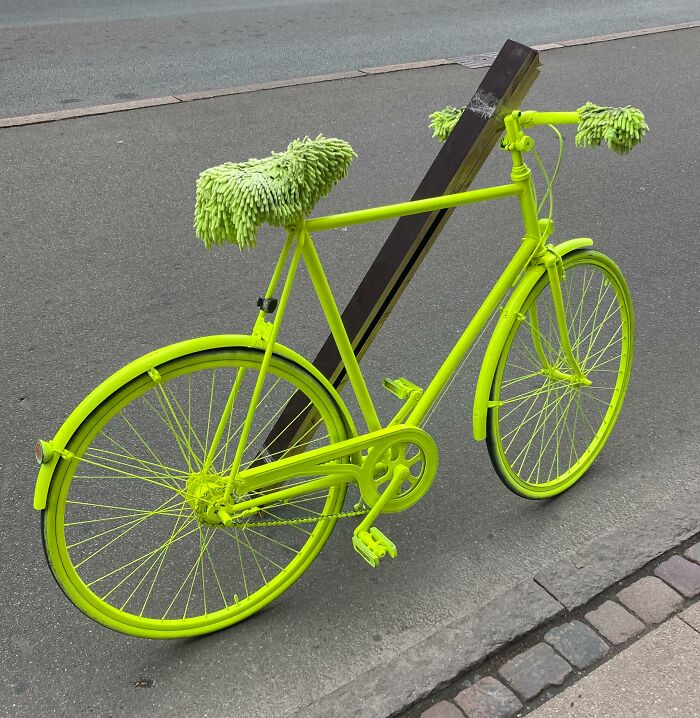 Bright neon green bicycle with fuzzy seat and handle grips parked on a street in Denmark, showcasing unique Danish design.