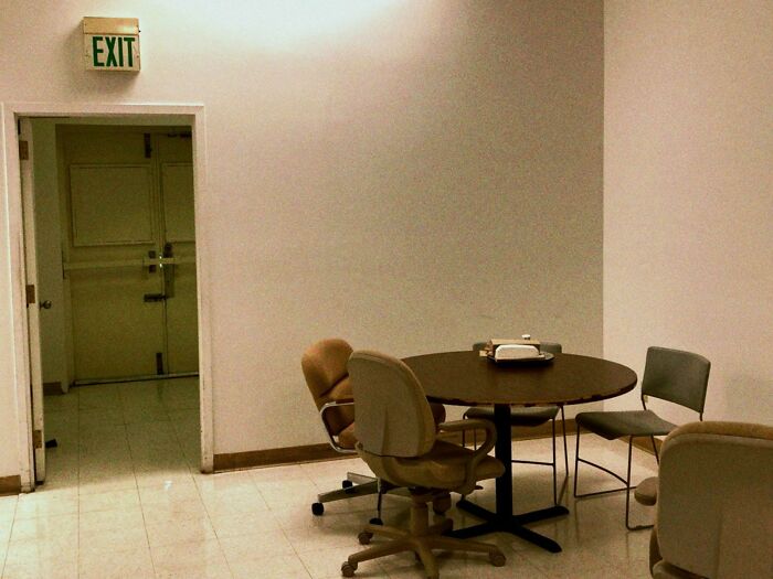 A bleak break room with mismatched chairs and a dull table, resembling one of the worst prison-like break rooms.