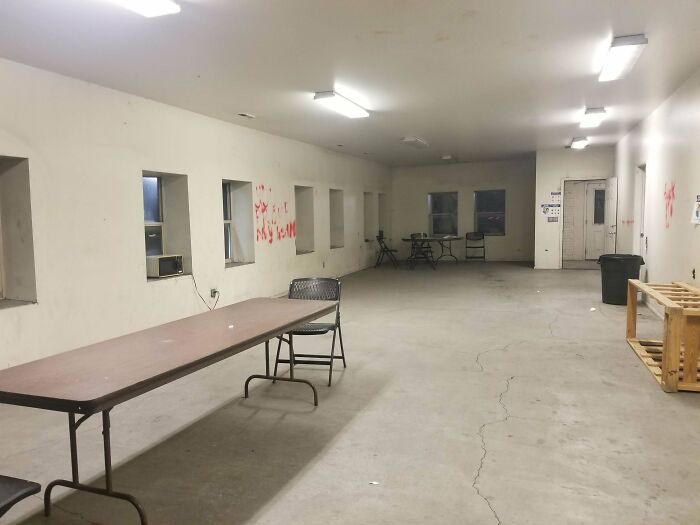 Sparse break room with concrete floors, folding tables, and chairs, resembling one of the worst prison-like break rooms.