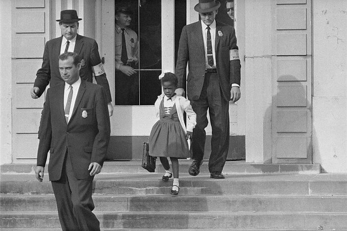 Little girl escorted by men in suits and hats walking down steps, illustrating random comparisons that affect perception of time.
