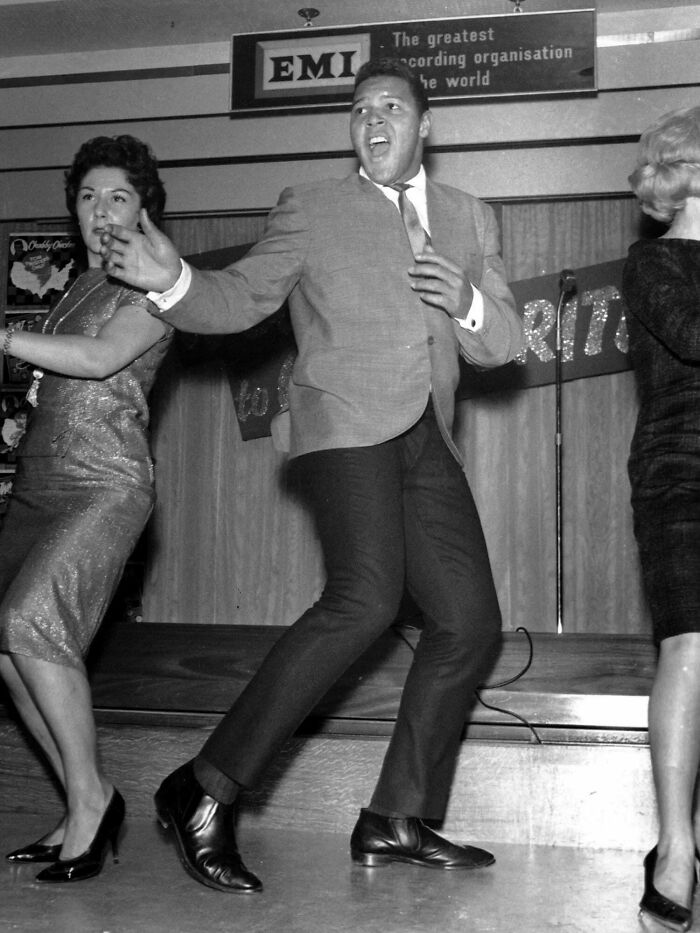 Man and two women dancing energetically on stage in a vintage setting, evoking a sense of time and perception contrasts.