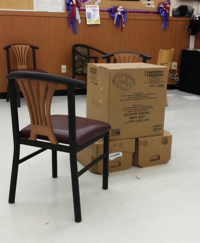 A break room with mismatched chairs and a makeshift table made from stacked cardboard boxes.
