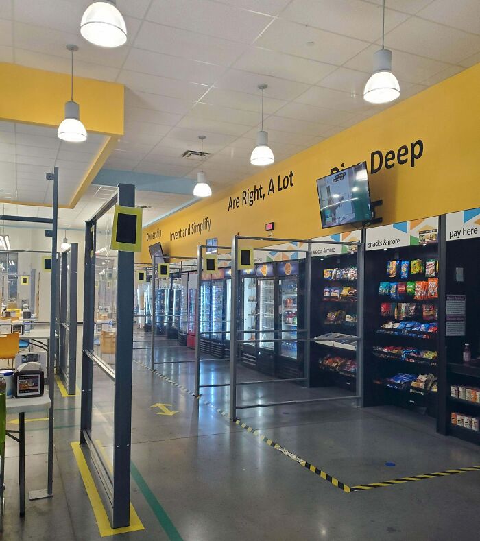 Break room resembling a prison with snack shelves, glass dividers, and a yellow wall in an institutional setting.