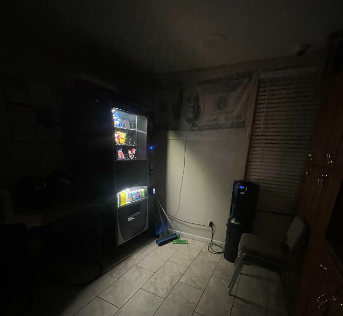 Dimly lit break room with a vending machine and minimal seating, resembling one of the worst break rooms ever.