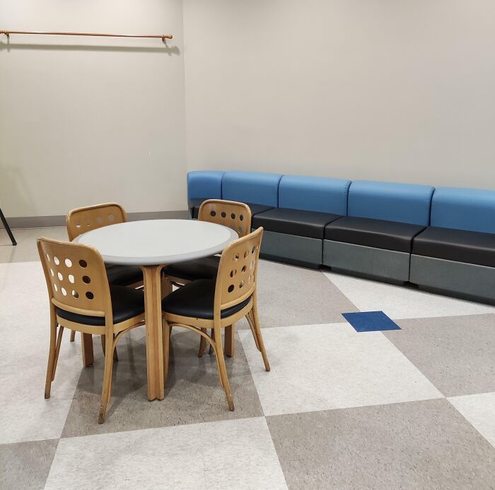 Break room with basic wooden chairs and bench seating in a sparse room, resembling one of the worst break rooms ever.