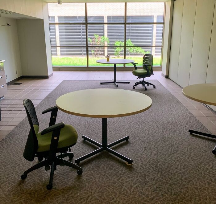 Sparse break room with minimal furniture and large windows, resembling one of the worst prison-like break rooms.