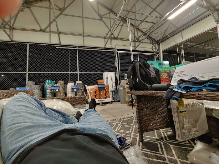 View from a reclined person in a poorly furnished break room resembling a prison setting with metal fencing and sparse seating.