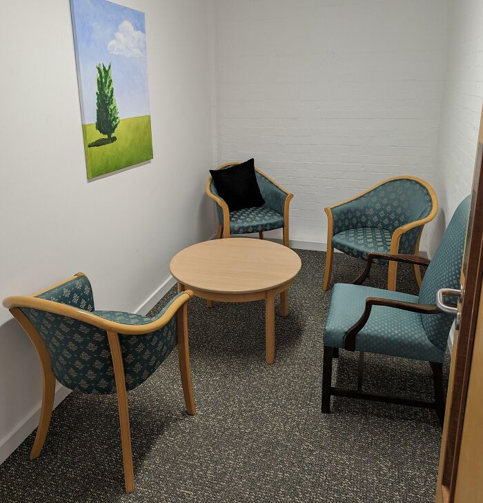 Small break room with mismatched chairs and a plain table in a space that looks like a prison break room.