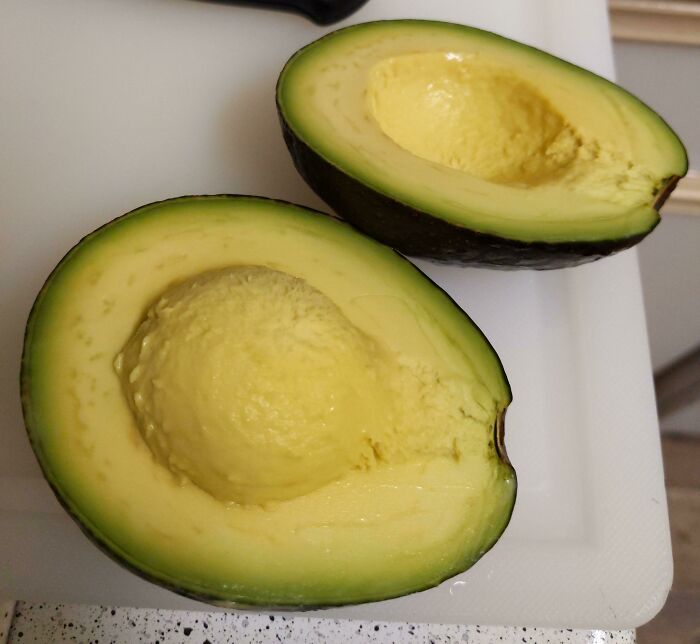 Halved avocado on a white cutting board, showcasing one of the everyday things that humble fully grown adults.