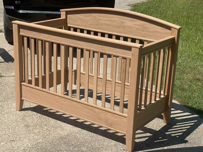 Woodworkers crafted a smooth wooden baby crib with slatted sides, showcasing their skill in incredible woodworking projects.