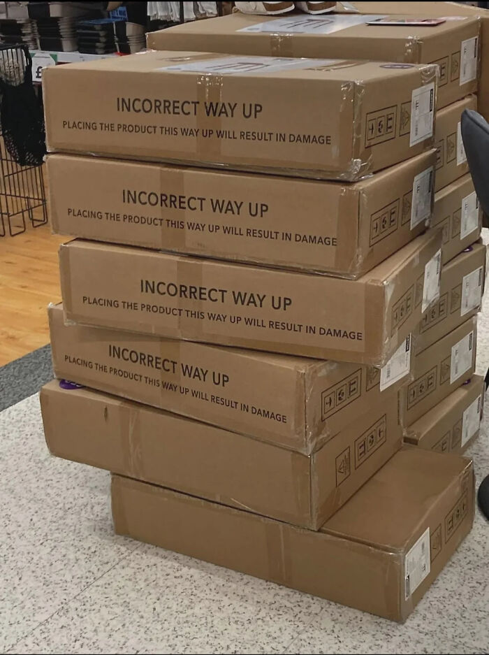 Stack of boxes labeled incorrect way up, illustrating You Had One Job fails and lack of common sense in handling packages.