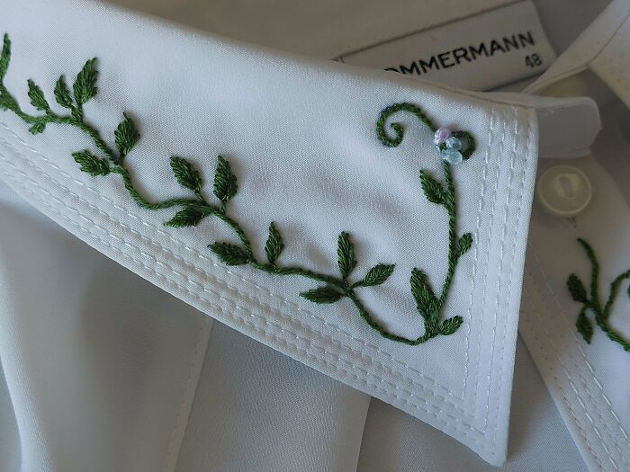 Close-up of a white shirt collar with delicate green vine embroidery creations, inspiring a new hobby.