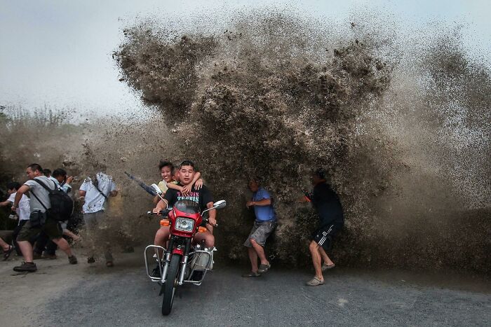 People reacting as a massive wave of mud erupts, captured in a perfectly timed photo showing dramatic natural motion.