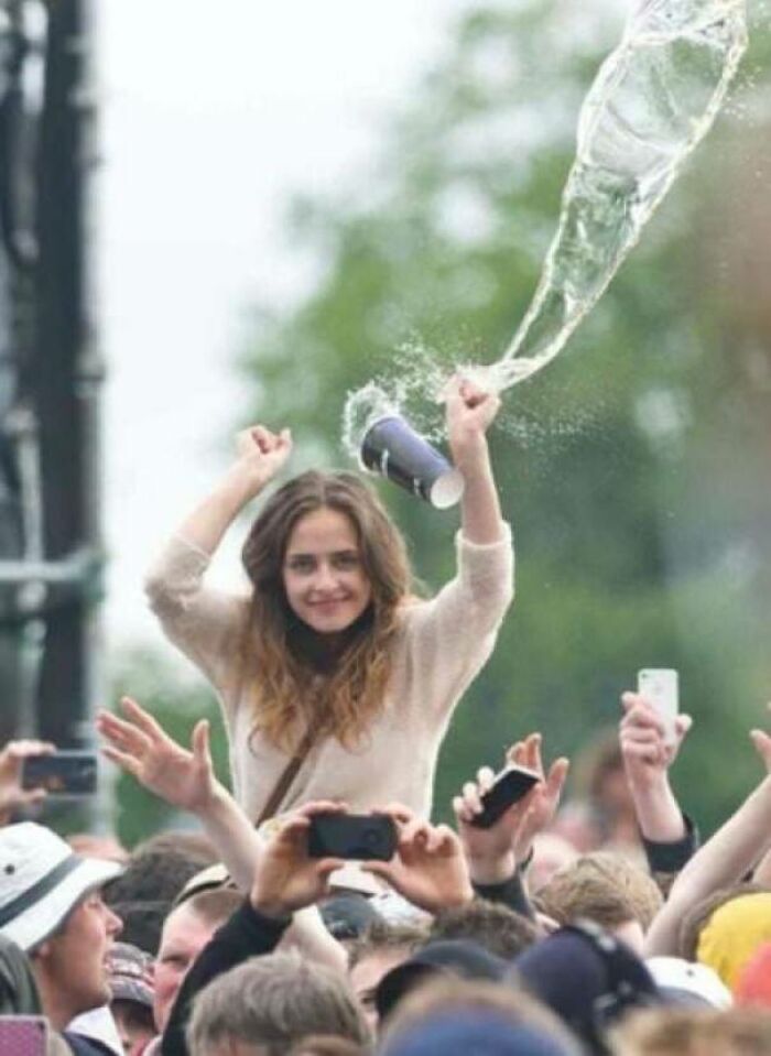 Young woman at a crowded outdoor event captured in a perfectly timed photo with water splashing from a cup.