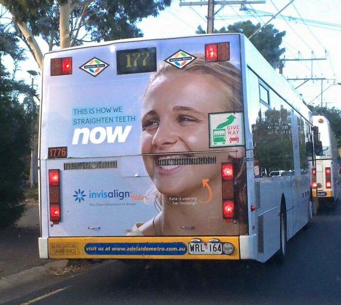 Bus advertisement fail showing a smiling woman with braces aligned awkwardly with the bus's rear lights and features.