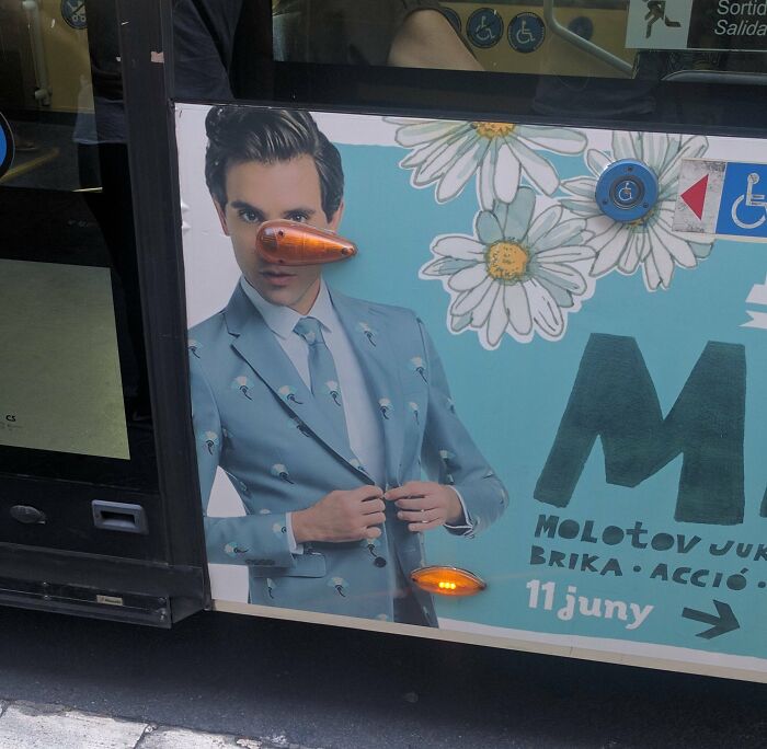 Humorous advertising placement fail showing a man with bus light positioned as a long nose on the ad.
