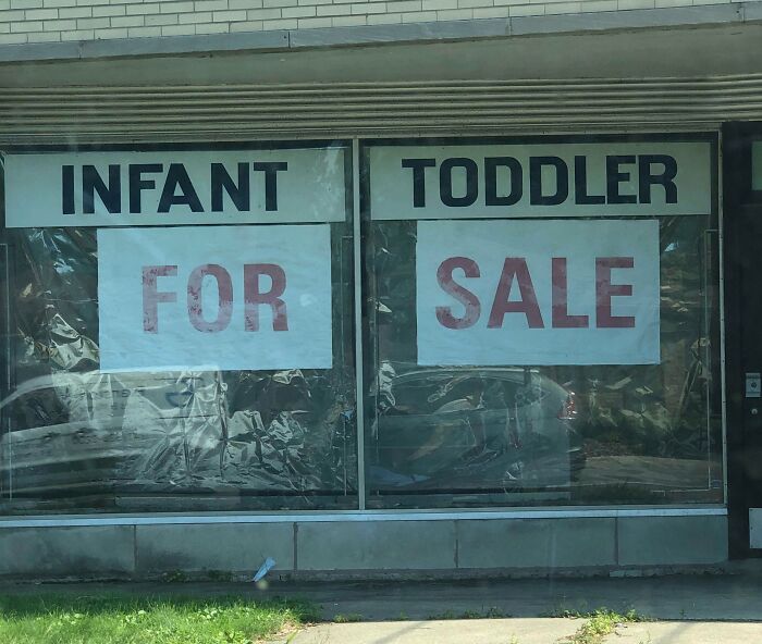 Window advertisement with infant and toddler signs placed separately, creating an advertising placement fail that amuses viewers.