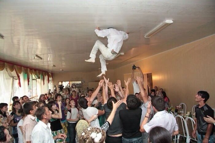 Person caught perfectly timed mid-air toss at a lively gathering, showing a rare moment better than any Photoshop effect.