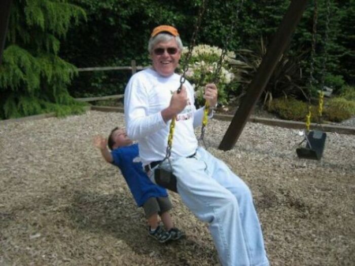Man and child on swing creating perfectly timed photo with child appearing to float behind in a playful outdoor moment