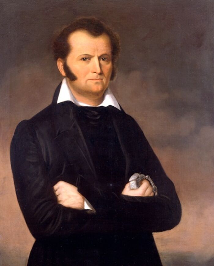 Portrait of an American folk hero with arms crossed, wearing black coat and white shirt, symbolizing historic folk heroes.