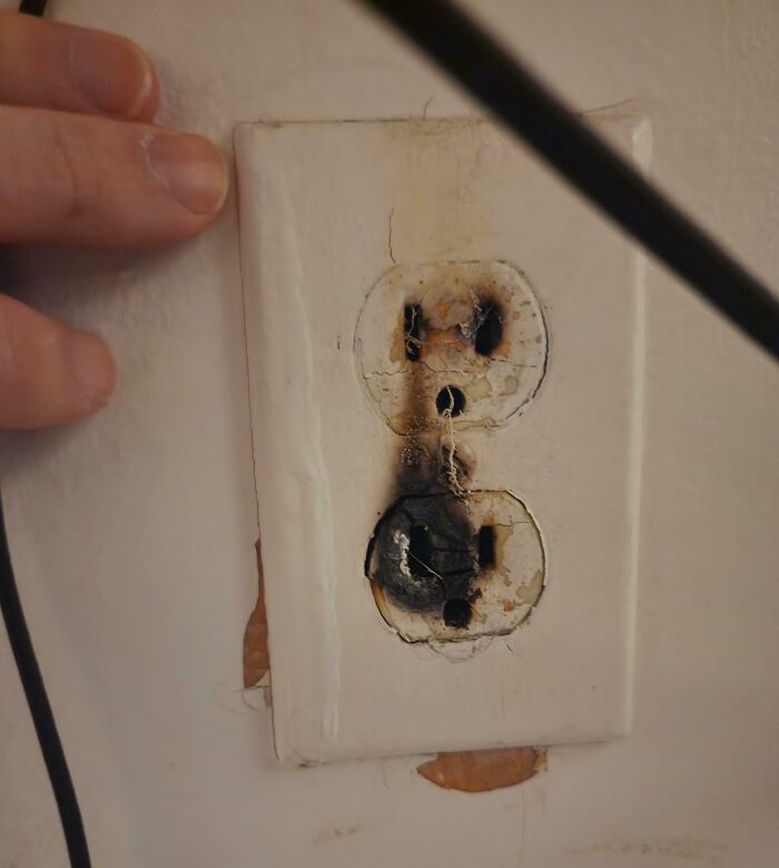 Burnt electrical outlet on a wall, showing damage and safety hazard from neglect by landlords in rental properties.