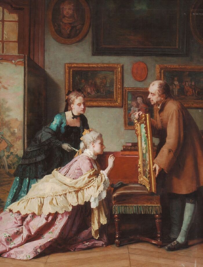 Victorian era scene with two women and a man examining a framed painting in a room filled with artwork.