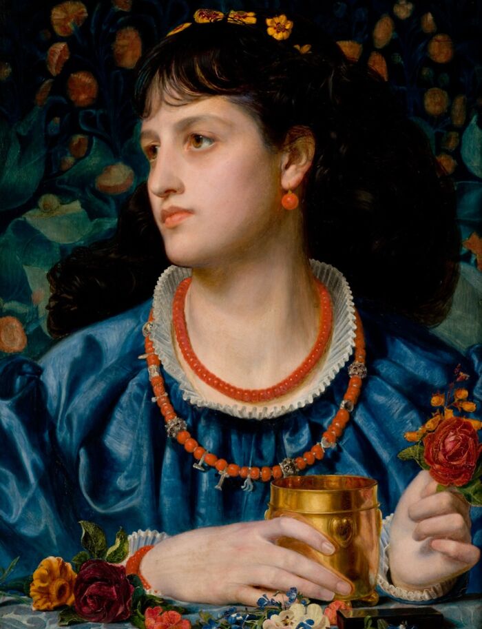Victorian woman in blue dress wearing red jewelry holding a gold cup, surrounded by flowers in a dark setting.