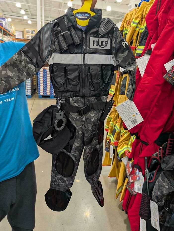 Child police costume in camouflage pattern with handcuffs and radio hanging on a store display in the US