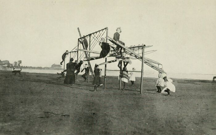 Black and white historic photo of children playing on a risky playground structure showing old playground safety hazards.