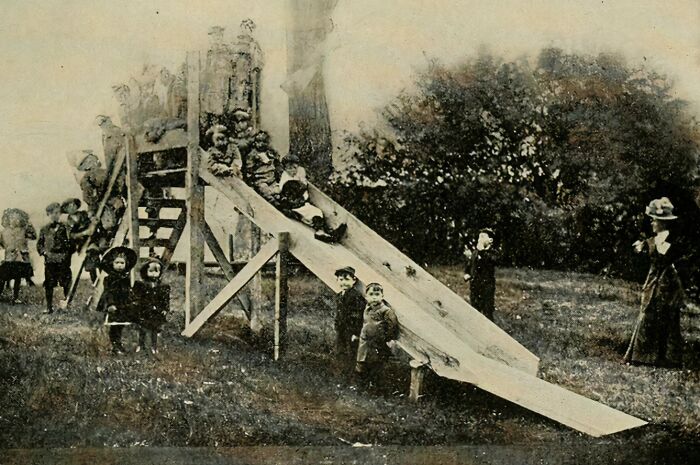 Historic photo of a playground slide with children playing, illustrating how being a kid back then was a life risk.