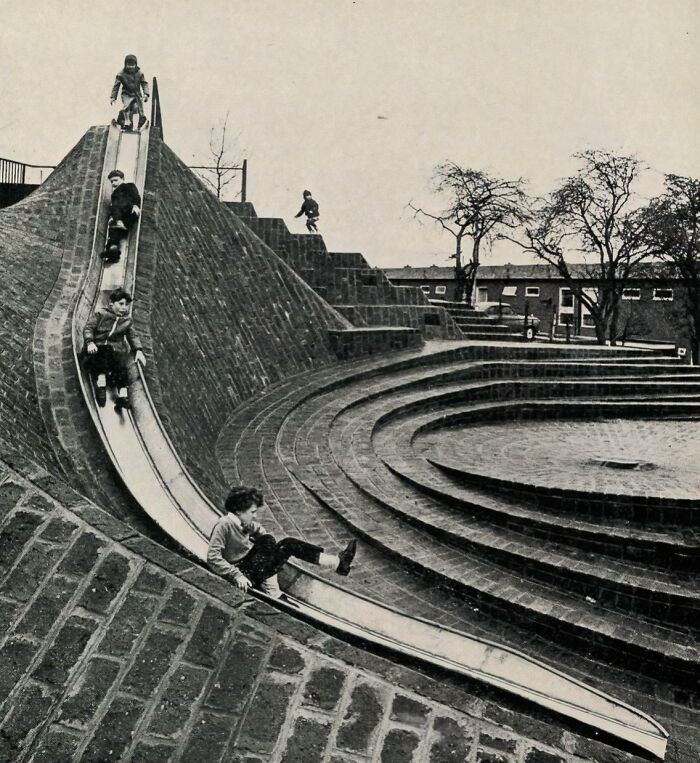 Historic playground photo showing kids sliding down a steep slide on a brick structure reflecting risky childhood play.